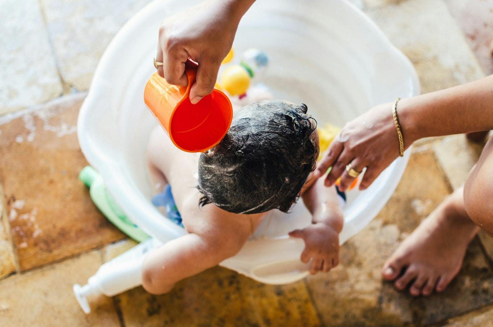 A caring parent bathing a baby in an outdoor setting. Playful and warm moment.