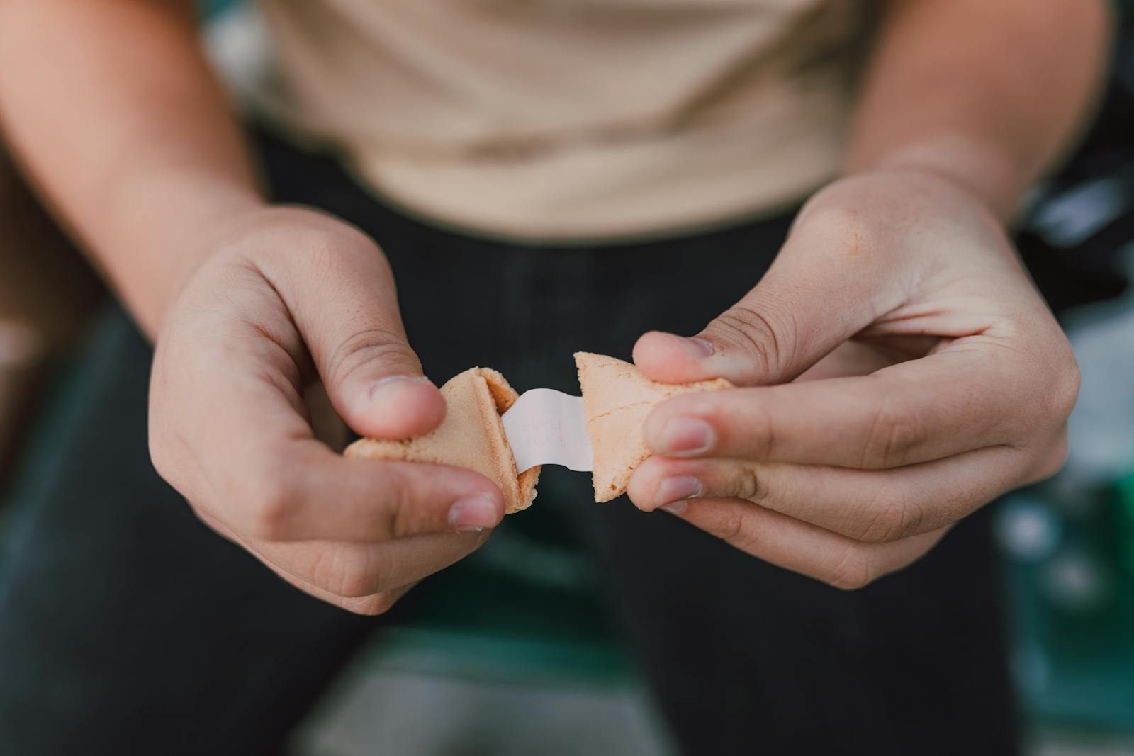 Hands breaking open a fortune cookie with a blank paper slip emerging.