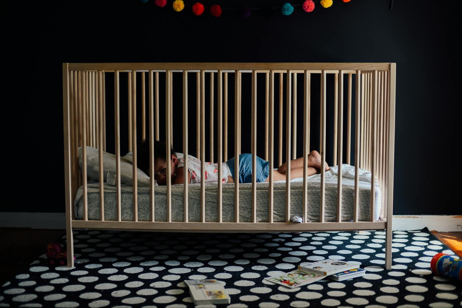 A baby peacefully sleeping in a crib inside a colorful and cozy nursery with soft lighting.