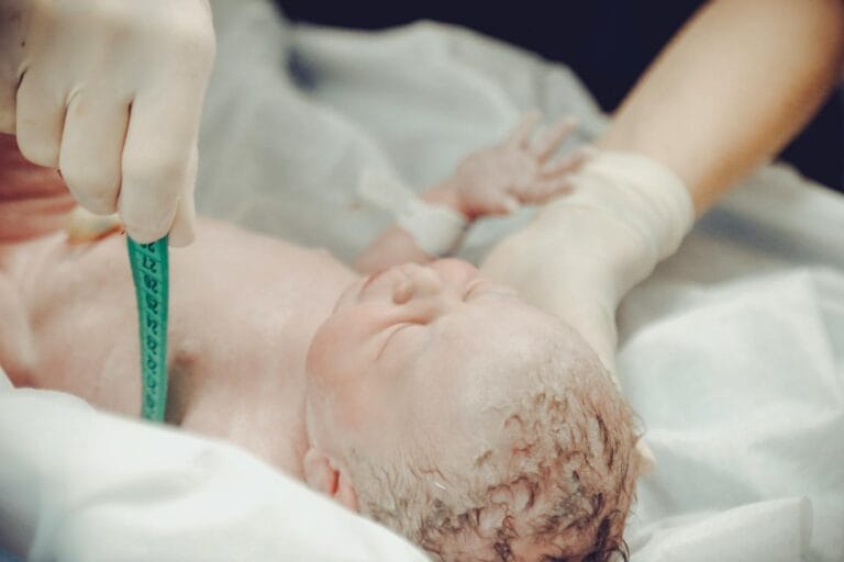 A newborn baby being measured by a medical professional in a hospital setting.
