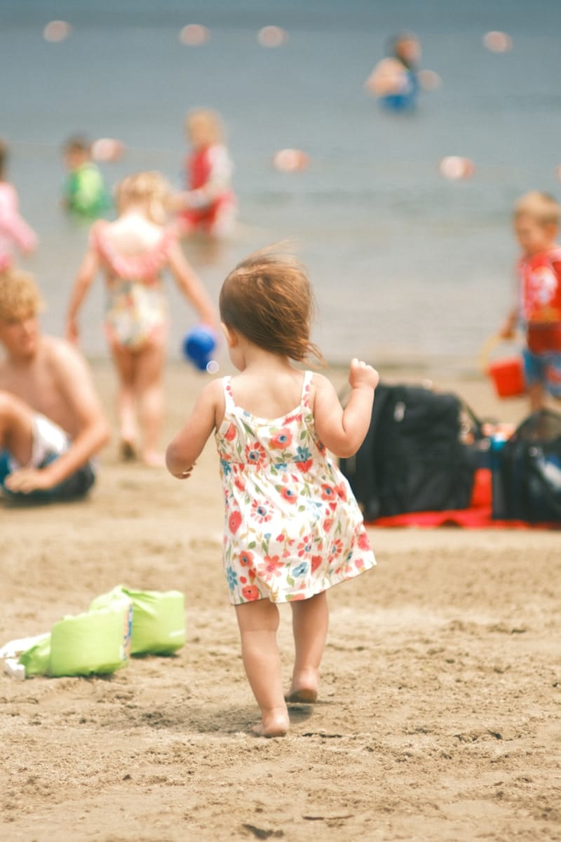 A toddler runs towards the water on the beach.