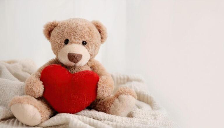 Teddy bear hugs a red heart.